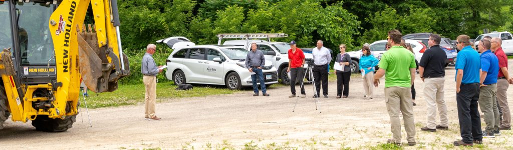 AcenTek's CEO Mike Osborne speaking at our groundbreaking event for laying new fiber optics at a rural location. He is speaking in front of the news and a crowd.